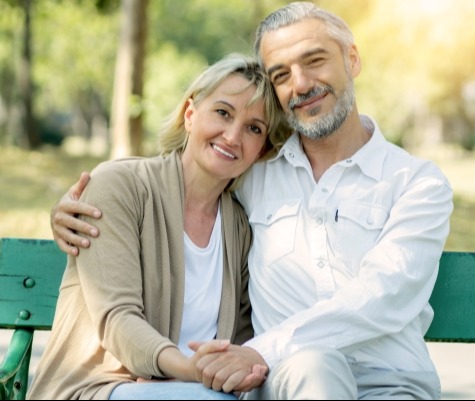 Retired couple sitting on bench in park